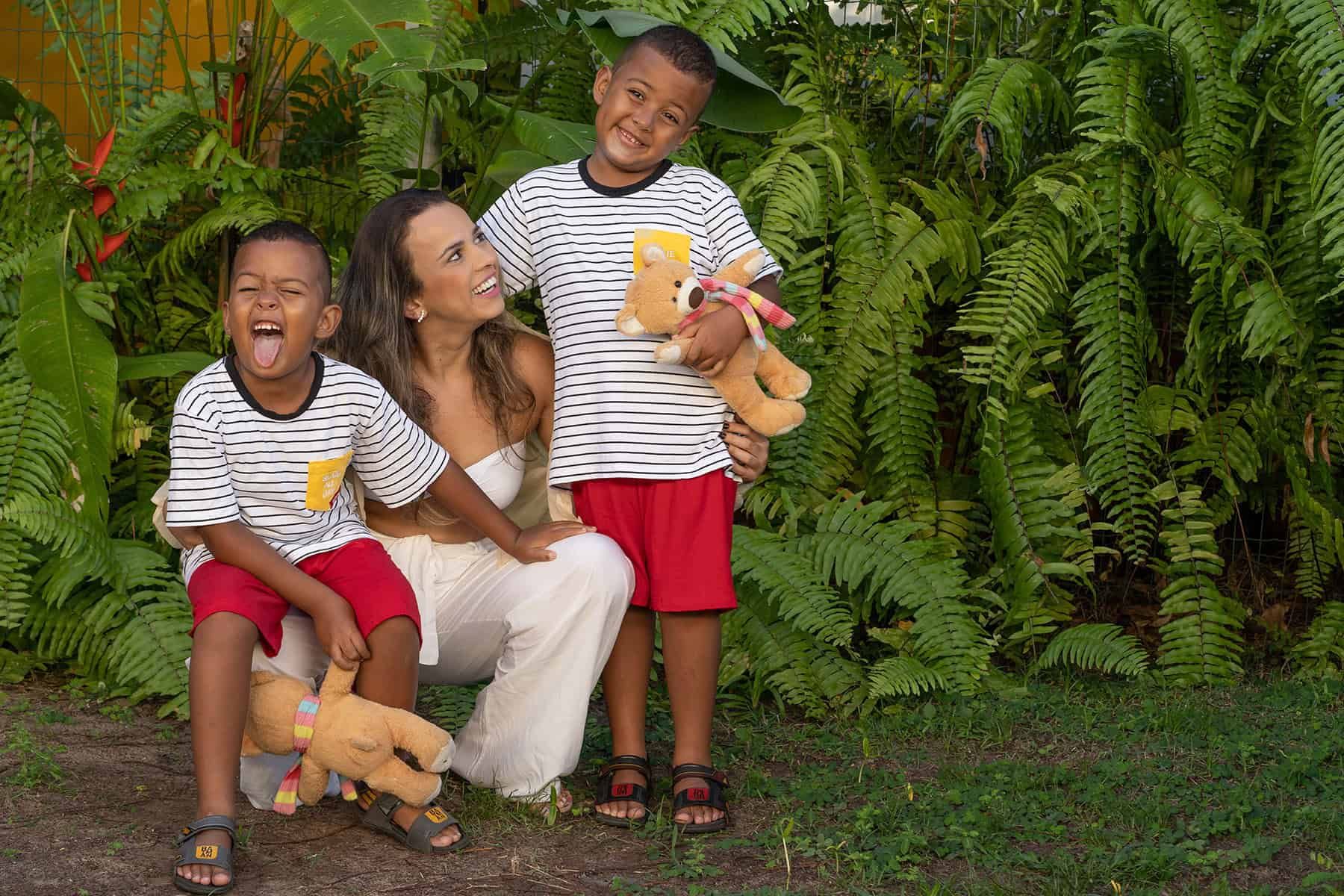 A mother and her two children sharing a playful portrait among green ferns
